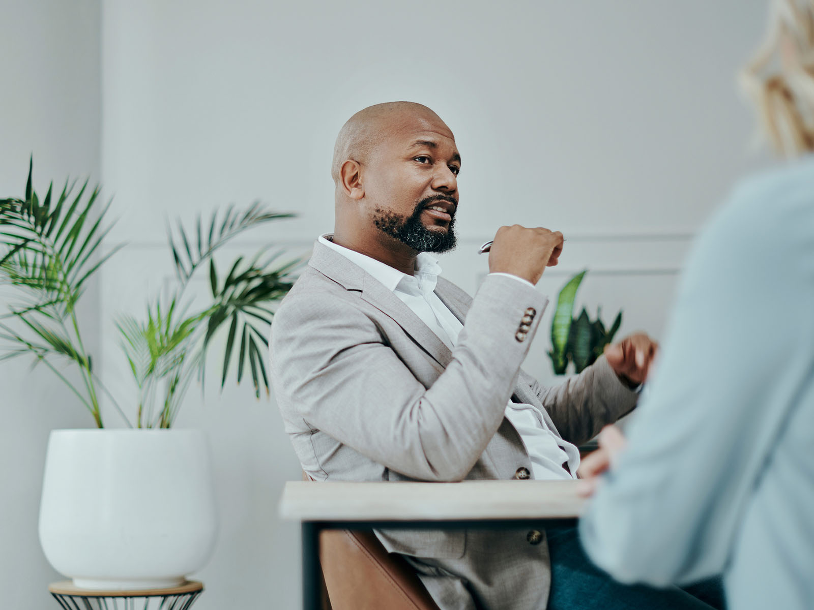 A man in a suit sat at a table having a conversation with a lady wearing blue