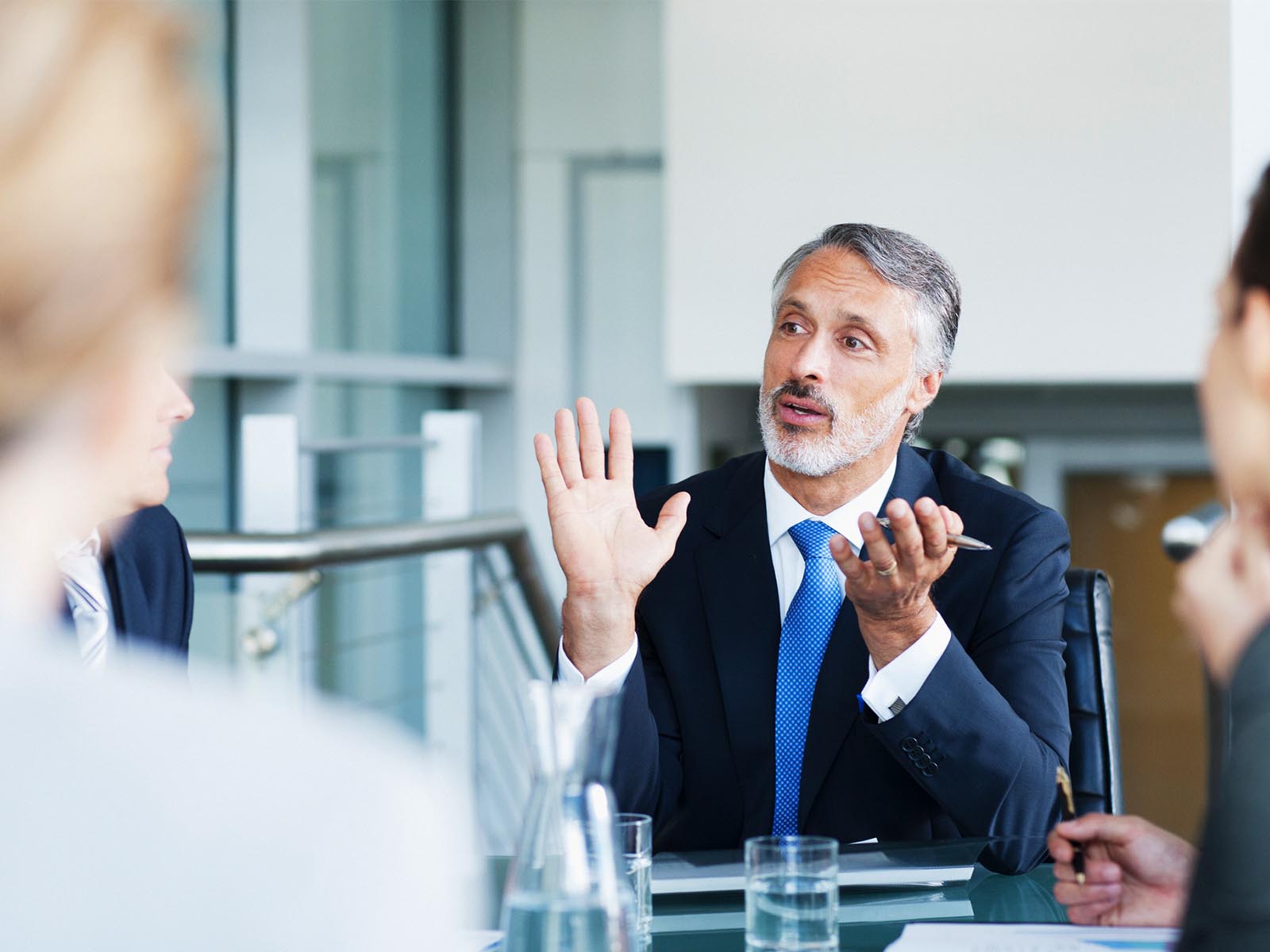 A middle-aged gentleman wearing a blue suit having an in-depth discussion during a meeting