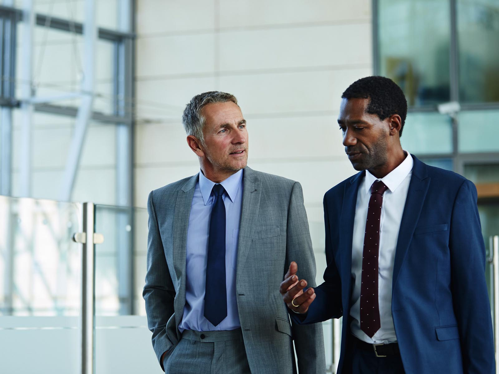 Two gentlemen in suits having a discussion while walking through an office