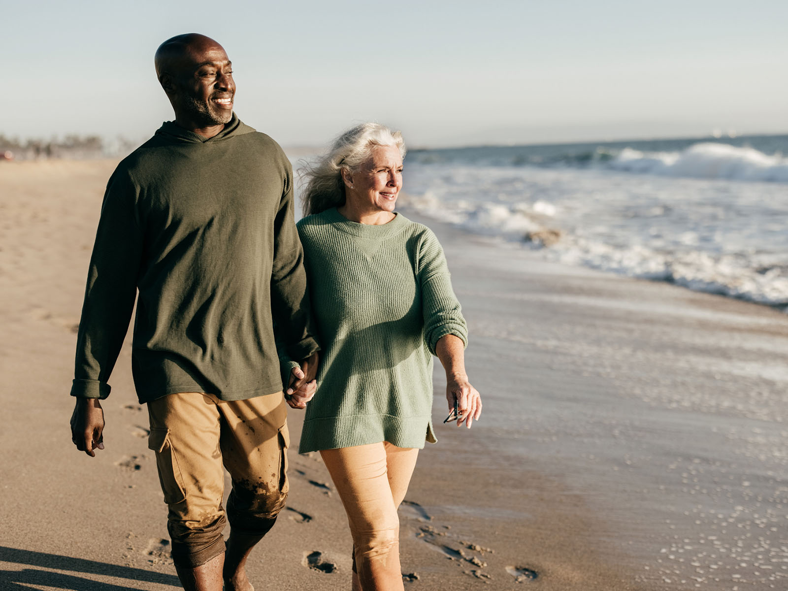 Two elderly people walking on the beach