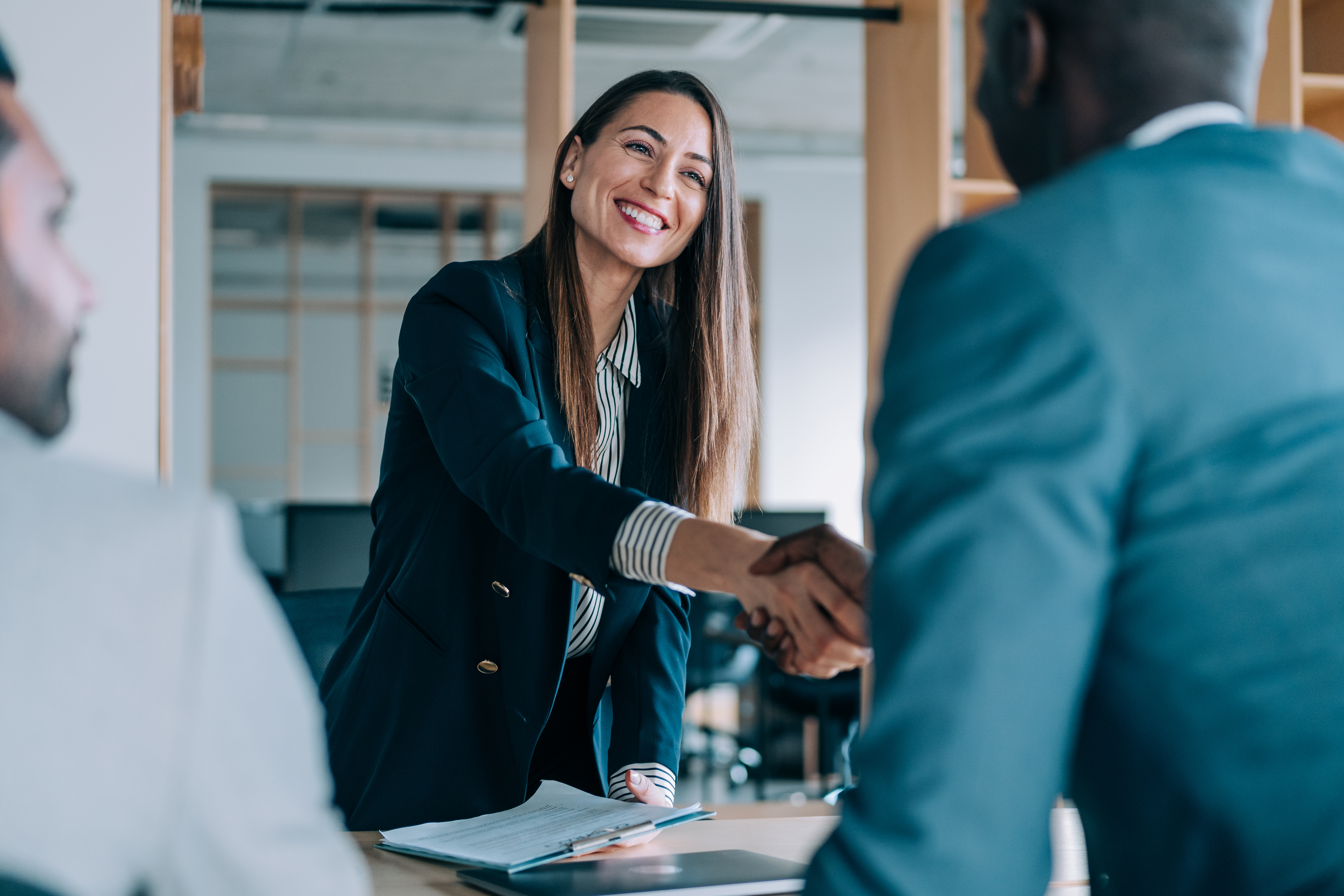 Womanleans Over Table To Shake Hands In A Meeting